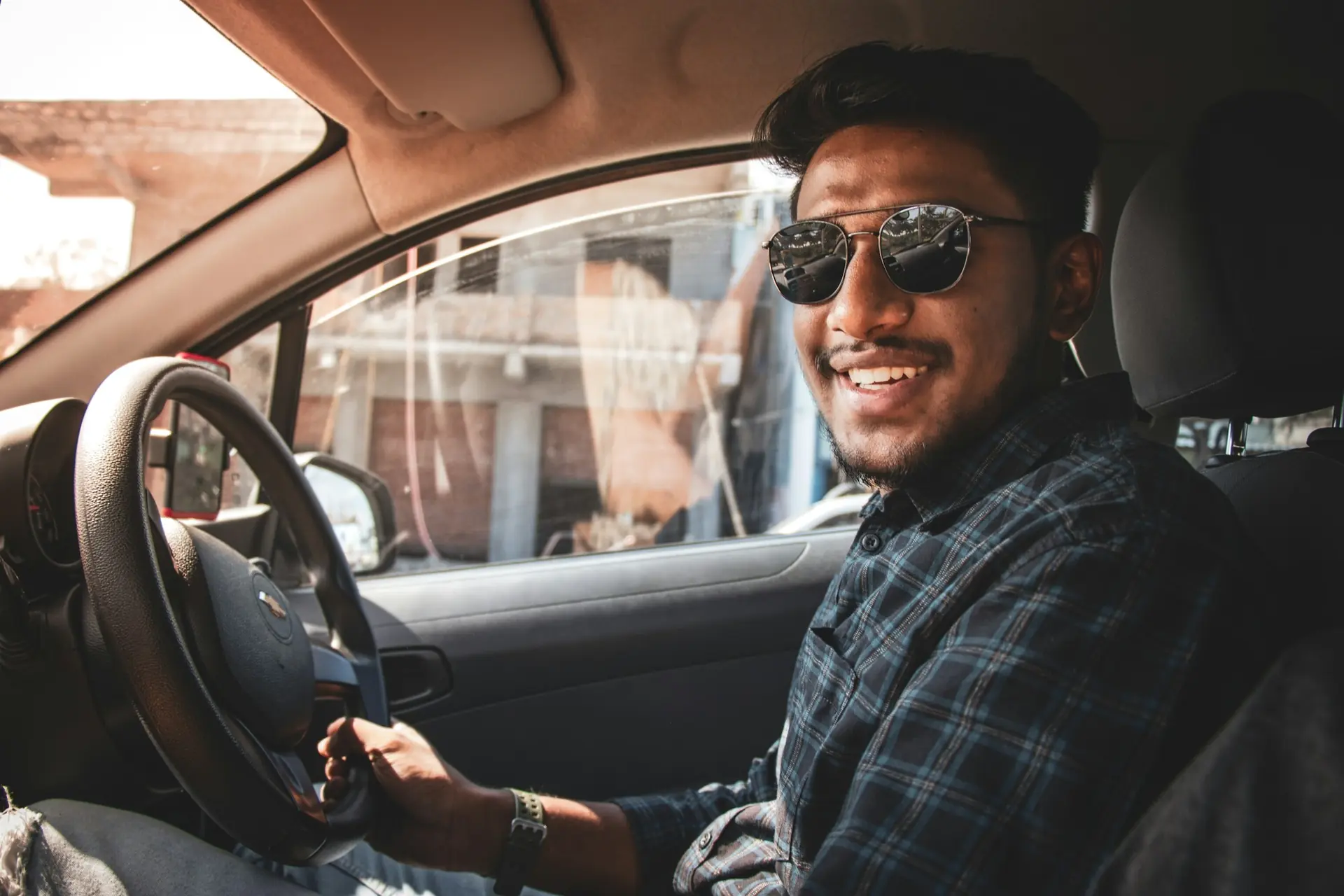 Un conducteur souriant au volant de sa voiture